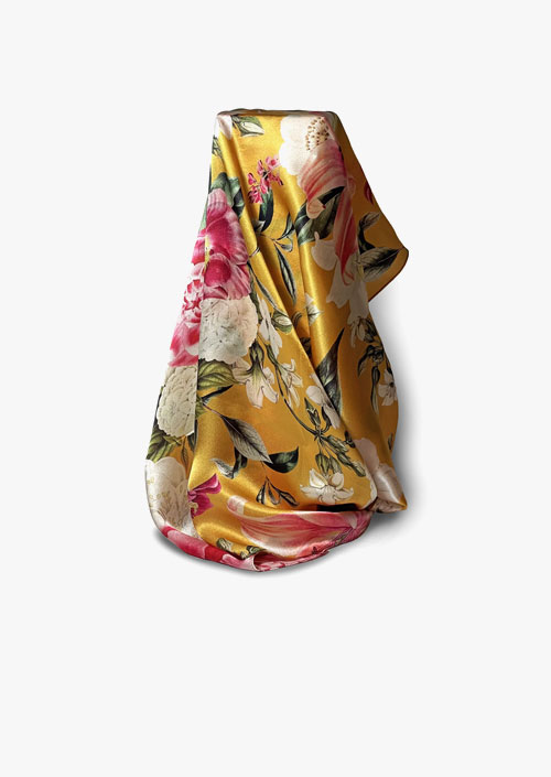 Pañuelo de seda con diseño floral sobre fondo ocre
